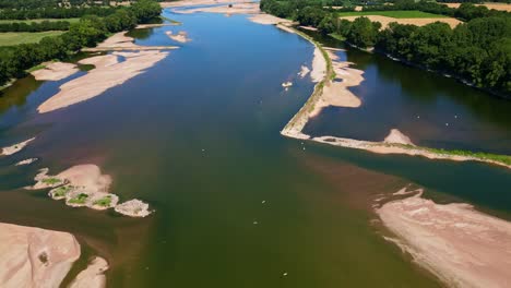 Drone top-down shot over Loire River pulling back and tilting up, revealing both banks, sandbanks, trees, and birds in flight - France