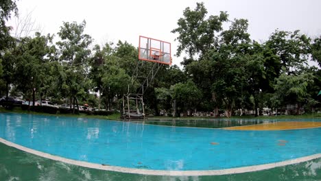 rain falling on outdoor basketball court floor in the park.