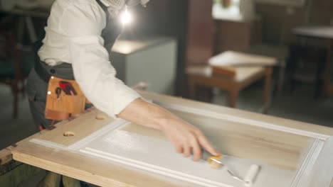 close-up of male hands with a roller painting the door in white