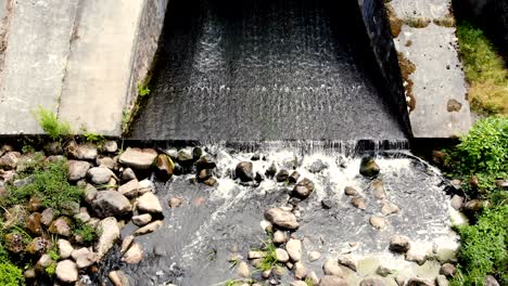 aerial view of water rushing through the gates at a dam and bridge