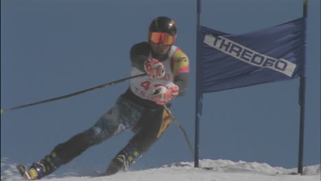 a competitive skier passes a sign as he skis downhill