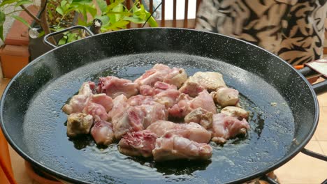 trozos de pollo cortado salteado en una sartén de paella