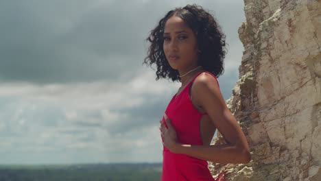 beautiful woman in red dress posing on a cliff