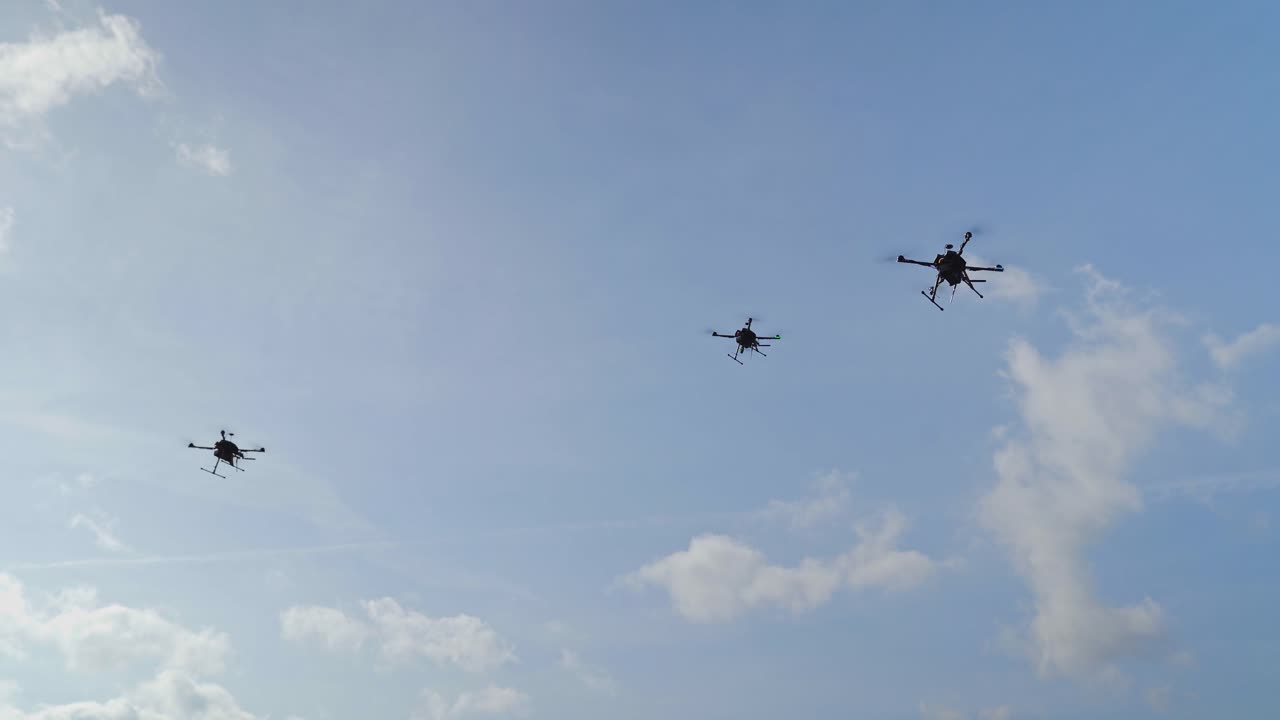 푸른 하늘과 구름에 대항하여 공중에서 날아다니는 세 대의 군사 드론