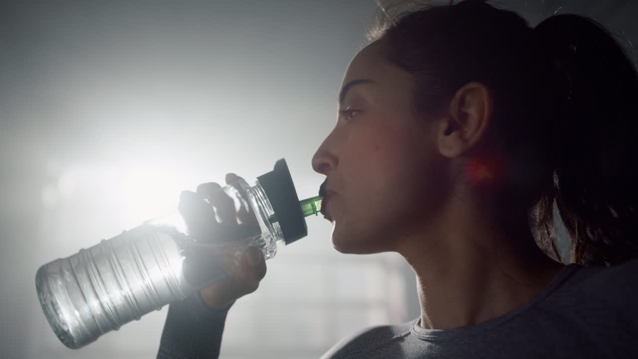 niña bebiendo agua de una botella de fitness. deportista de pie en un club deportivo