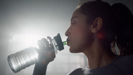 girl drinking water from fitness bottle. sportswoman standing in sport club