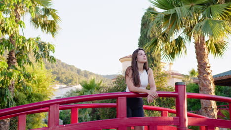 medium shot of a young woman looking around standing on a bridge