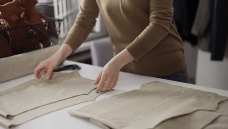 Unrecognizable-fashion-designer-or-tailor-working-with-fabric-patterns-at-the-studio