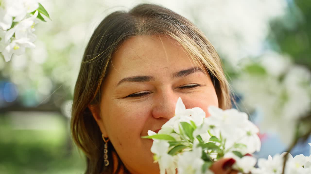 Woman smelling apple blossoms in spring