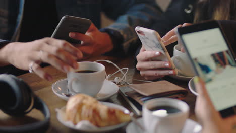 close up hands group of friends using smartphone mobile technology in cafe browsing online social media messages enjoying socializing together on internet connection