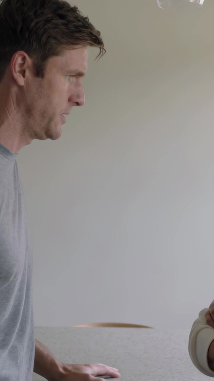 Vídeo vertical: Homem entrando, encostado no balcão em casa, de camiseta cinza, confrontando pessoa, com espaço para texto