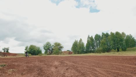 piloto de motocross montando en un camino de tierra y mirando a la cámara