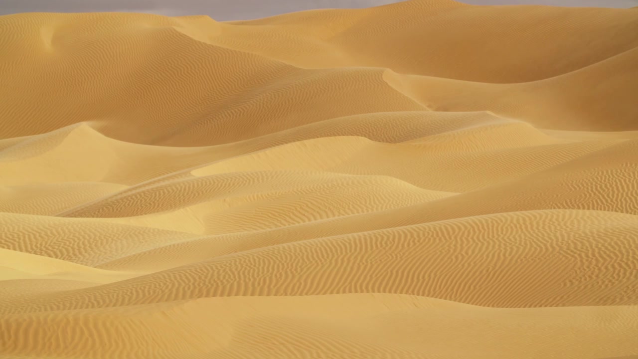 Ripresa ravvicinata con drone in movimento sulle creste delle dune sahariane in Tunisia, che evidenzia gli intricati motivi geometrici creati dal vento e dalla sabbia.