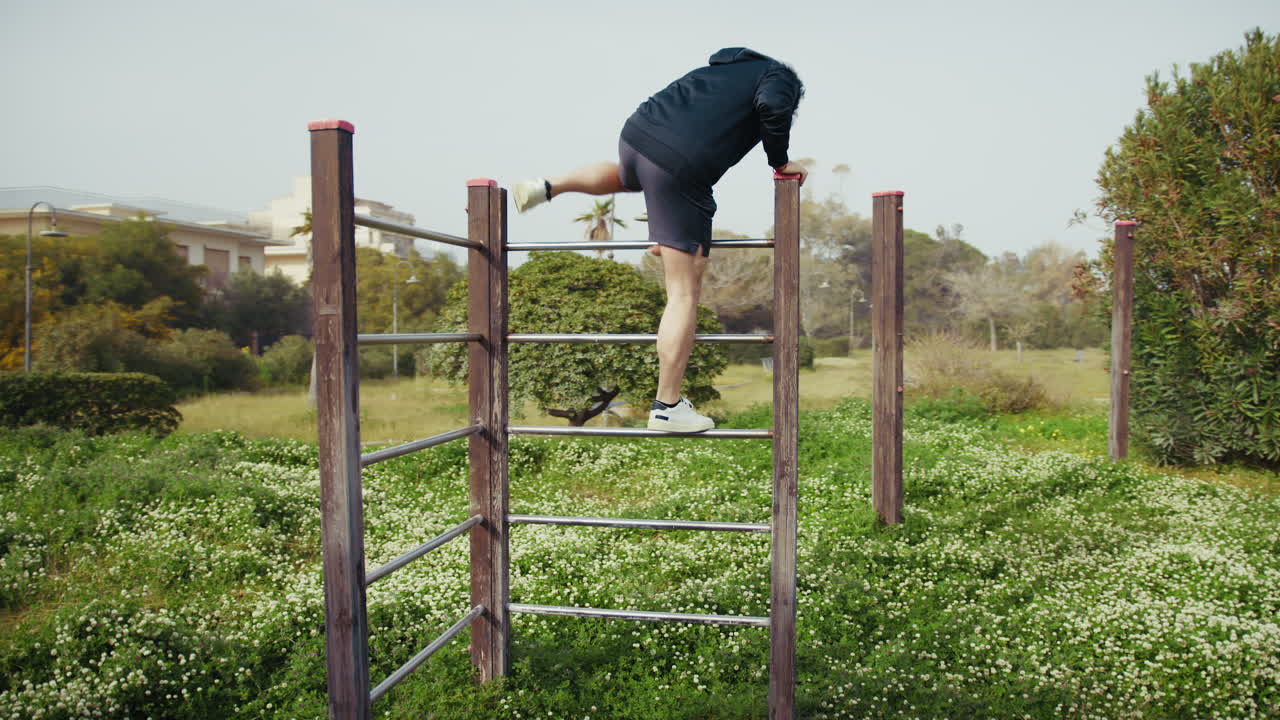 Man Trains on Iron Bars in the Park Surrounded by Nature