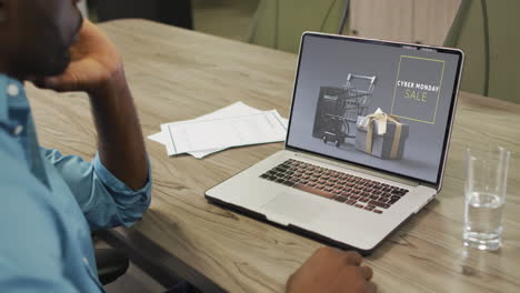 hombre afroamericano en la mesa usando una computadora portátil, compras en línea durante la venta de cyber monday, cámara lenta