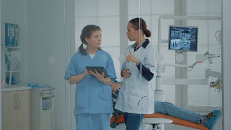 professional dentist talking to nurse and looking at digital tablet