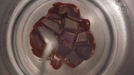vista de cerca de una persona mezclando chocolate de un tazón en un baño maría