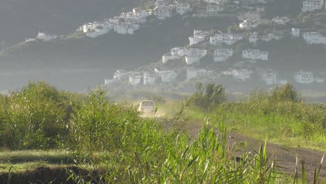 4x4-SUV-driving-away-on-dirt-road-through-marshland-in-Spain,-Wide-shot