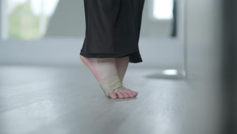 fit girl in black clothes performing contemporary. female dancer shows flowing motions, body and hands waves at white room. modern ballet dance choreography. young woman is moving smoothly