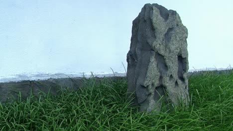 a decorative rock in a japanese garden with a white stucco wall in the background