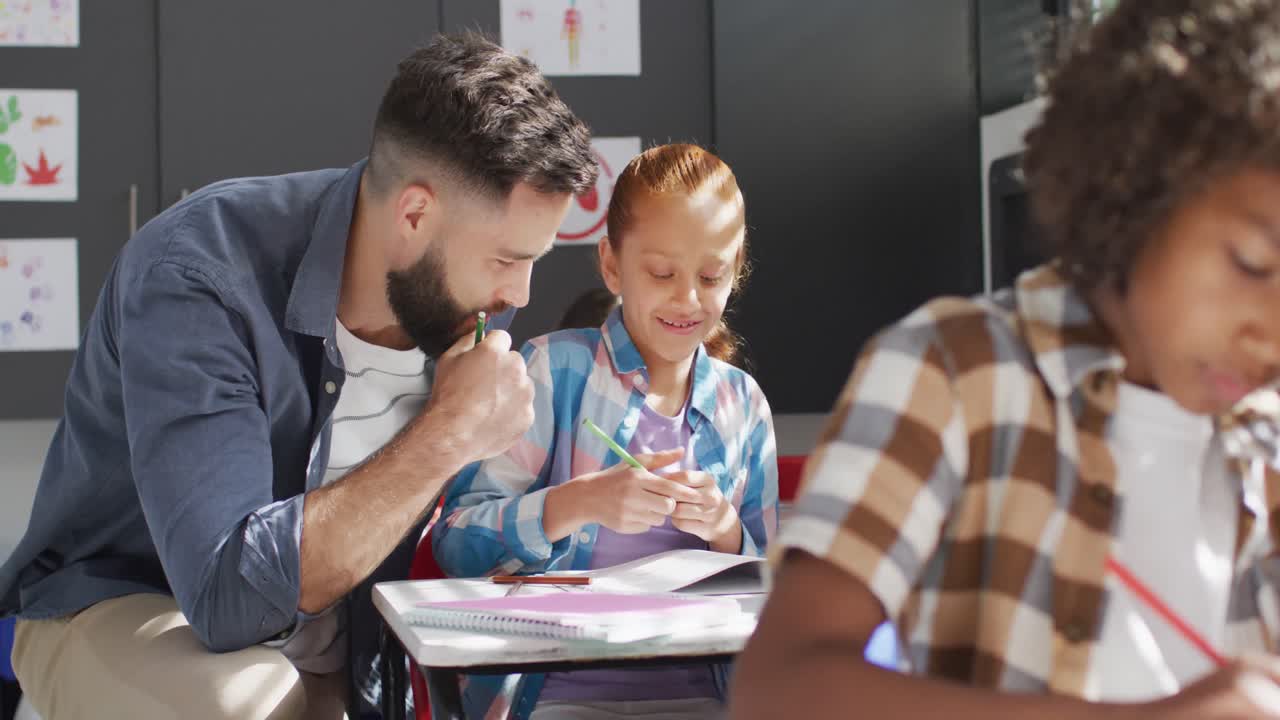 maestro masculino diverso y escolares felices sentados en el escritorio en el aula de la escuela