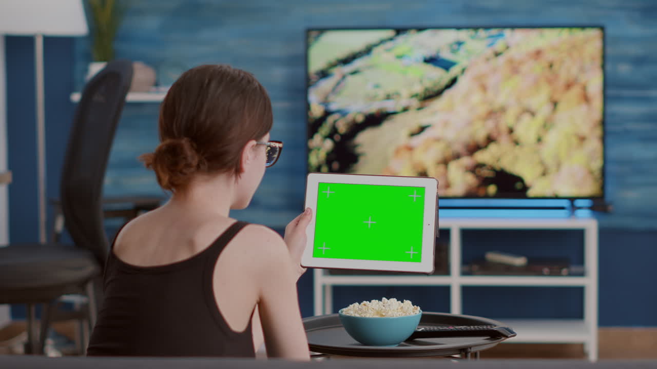 Closeup of young woman holding digital tablet with green screen watching online video content