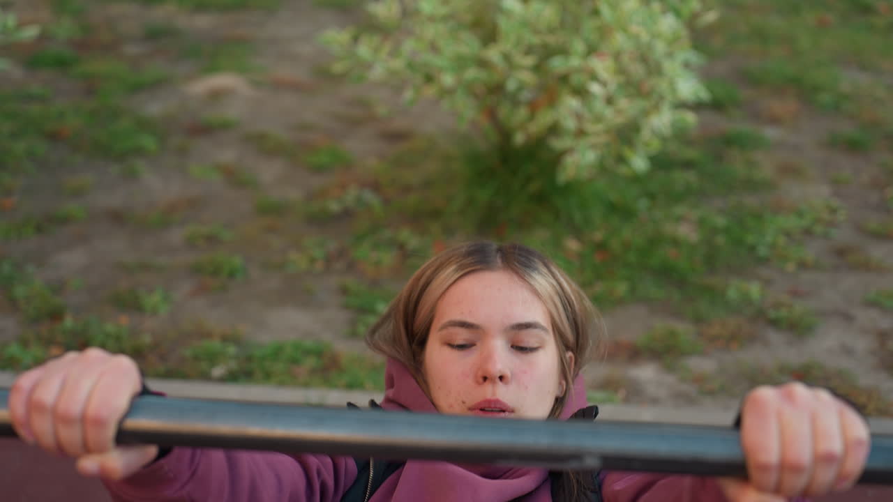 Aerial view of fit lifestyle advocate working out with much energy on horizontal bars in outdoor park, wearing athletic clothing, focused on strength training, healthy active lifestyle concept