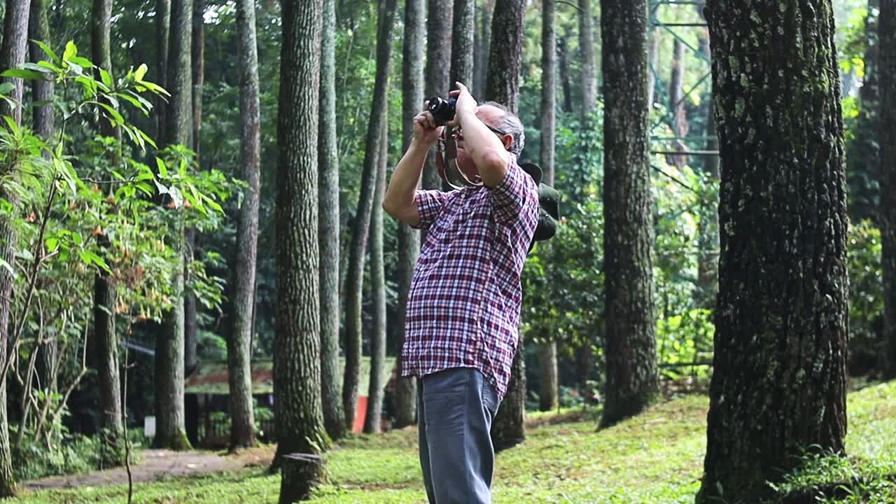 Elderly Man enjoys nature photography in forest capturing stunning landscapes on peaceful getaway
