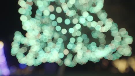 centelleantes luces de navidad cian y blancas borrosas con bokeh circular en el árbol