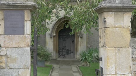 old church path leading to rustic wooden door. tree leaves rustling in the wind