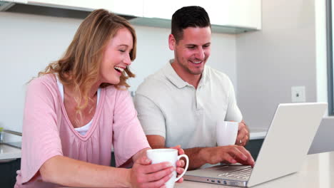 pareja feliz usando la computadora portátil juntos y tomando café