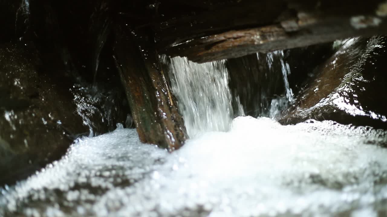 Close up gimbal shot of stream passing through branches and rocks