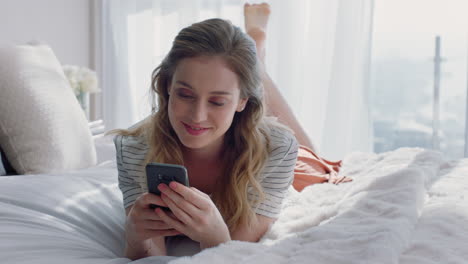 Schöne-Frau,-Die-Ihr-Smartphone-Nutzt,-Um-SMS-Zu-Schreiben,-Social-Media-Nachrichten-Zu-Durchsuchen-Und-Die-Mobiltelefonkommunikation-Zu-Genießen,-Die-Zu-Hause-Im-Bett-Liegt