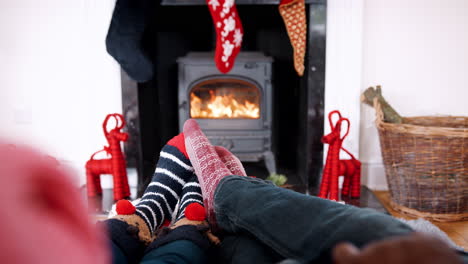 Low-section-of-couple-wearing-Christmas-socks-relaxing-in-front-of-fireplace,-detail