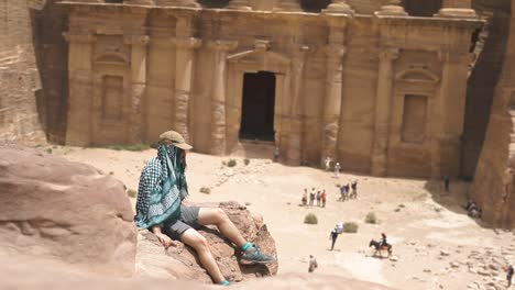 adventure man sitting in a rock, background temple, petra jordan, static shot