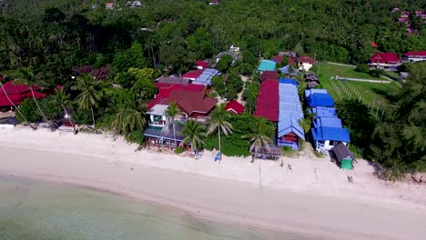 overhead aerial drone shot panning from left to right, showing the different accommodations that could be found in haad yao beach in kho phangan island in southern thailand