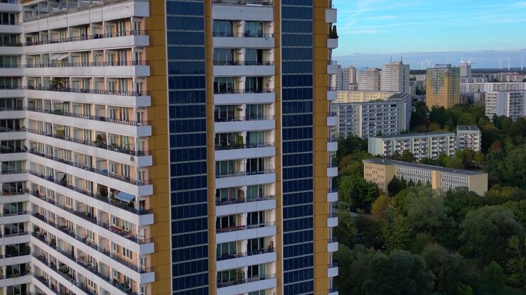 Facciata di un condominio in stile Plattenbau con pannelli solari installati, che rappresenta la vita urbana sostenibile e l'energia rinnovabile. Fantastica panoramica aerea con drone in avanzamento