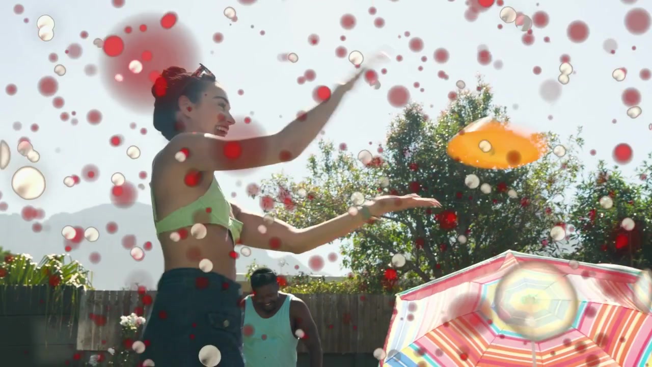 Man tossing disc backyard, woman catching returning disc, particles partly obscuring faces, leisure