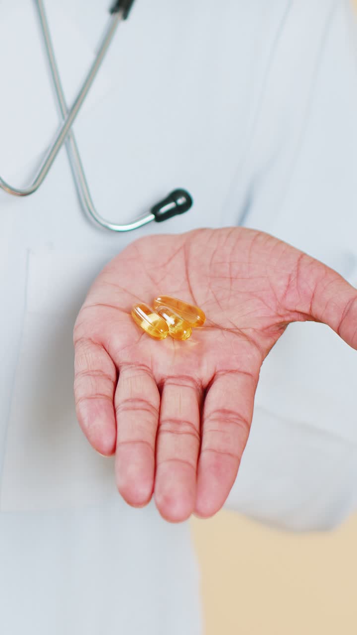 Seorang dokter pria menunjukkan pil tablet omega3 di telapak tangan merekomendasikan obat-obatan perawatan imunisasi vitamin