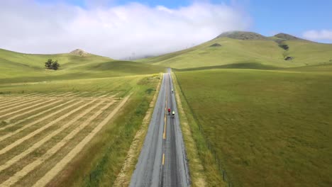 gente en bicicleta por una carretera asfaltada con paisaje de campo verde en san luis obispo, california