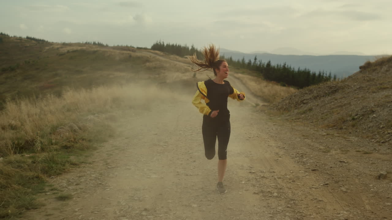 Donna che fa jogging in montagna. Atleta felice che si gode i buoni risultati dopo l'allenamento.