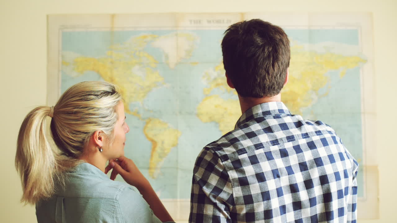 una joven pareja de turistas mirando el mapa del mundo