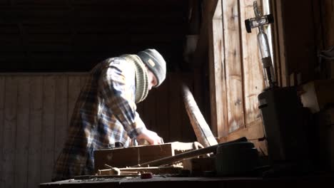 Adulto-Joven-Está-Trabajando-En-Un-Banco-De-Trabajo-Viejo-Y-Polvoriento,-Vista-Deslizante