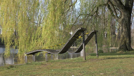 taped off wooden sun loungers in a public park near a pond