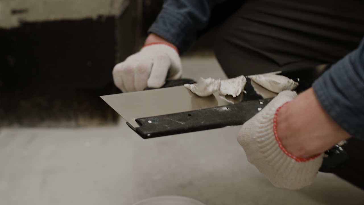 Close-up of a Person Using a Putty Knife to Apply Filler