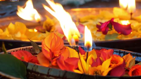 close-up of burning candles surrounded by flower petals in a bowl of water