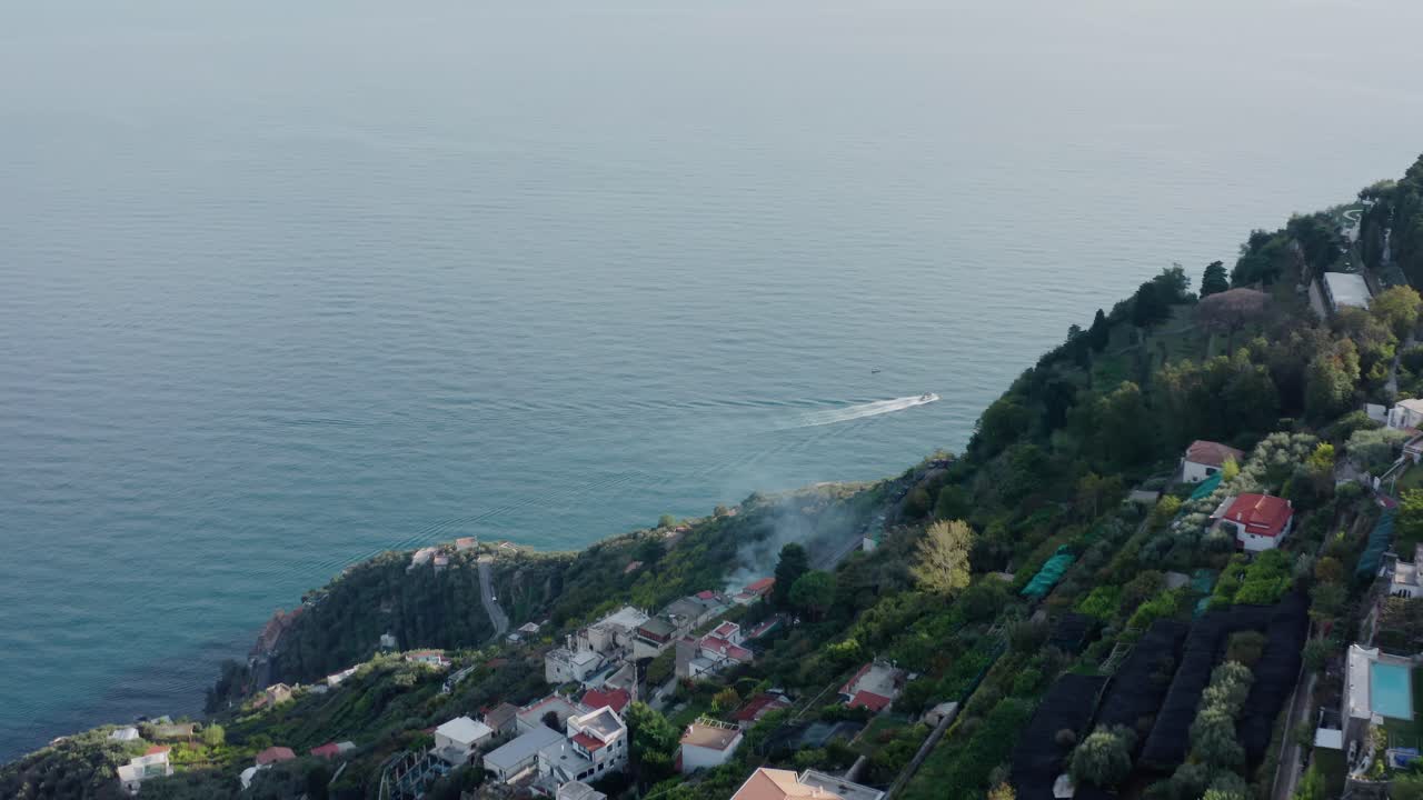 Vista aerea di un villaggio costiero e di una barca sul Mar Mediterraneo.