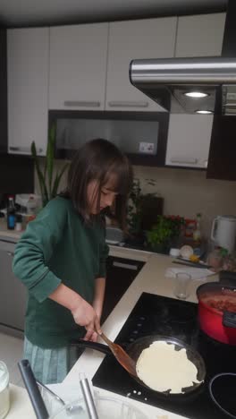 young girl cooking pancakes