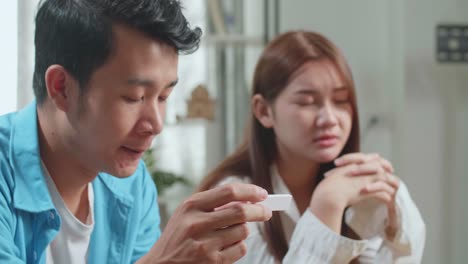 close up frustrated asian couple after checking a pregnancy test