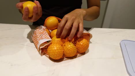 person picking oranges from a mesh bag